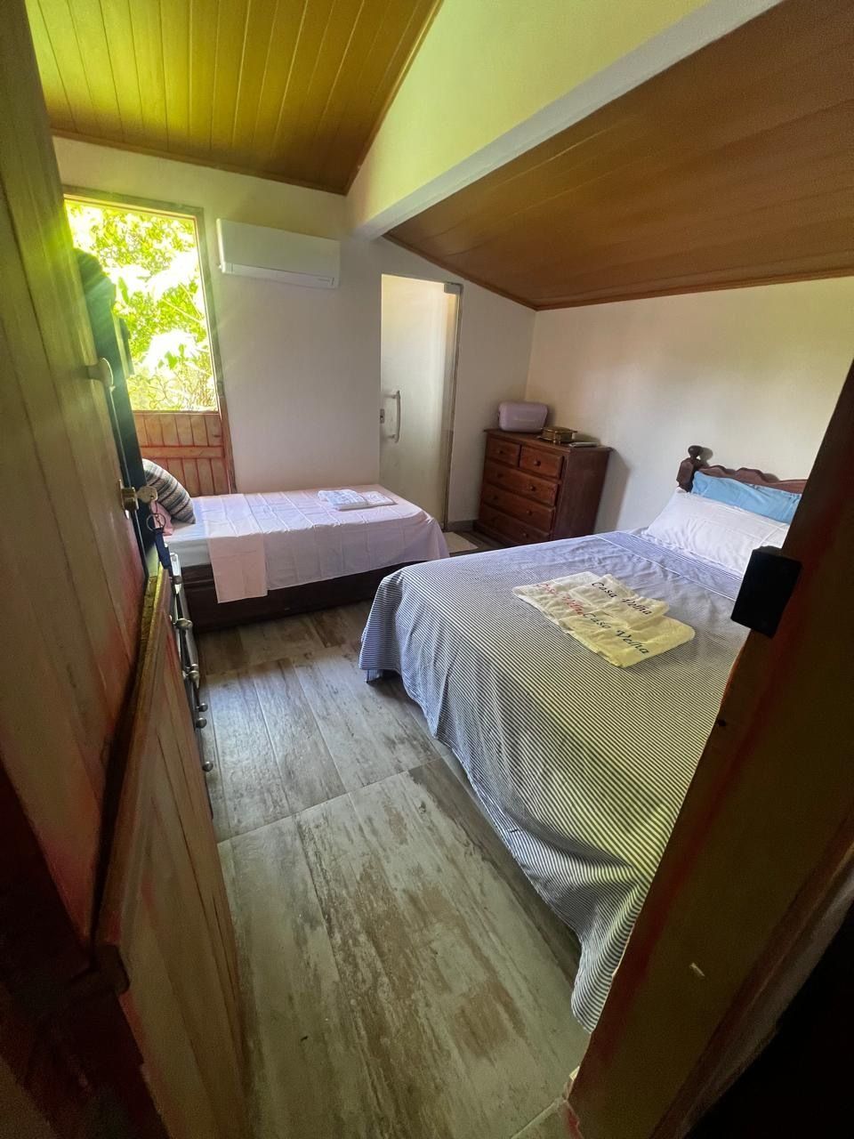 Un dormitorio con una cama, un aparador y un ventanal.