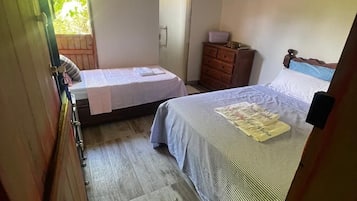 Un dormitorio con una cama, un aparador y un ventanal.