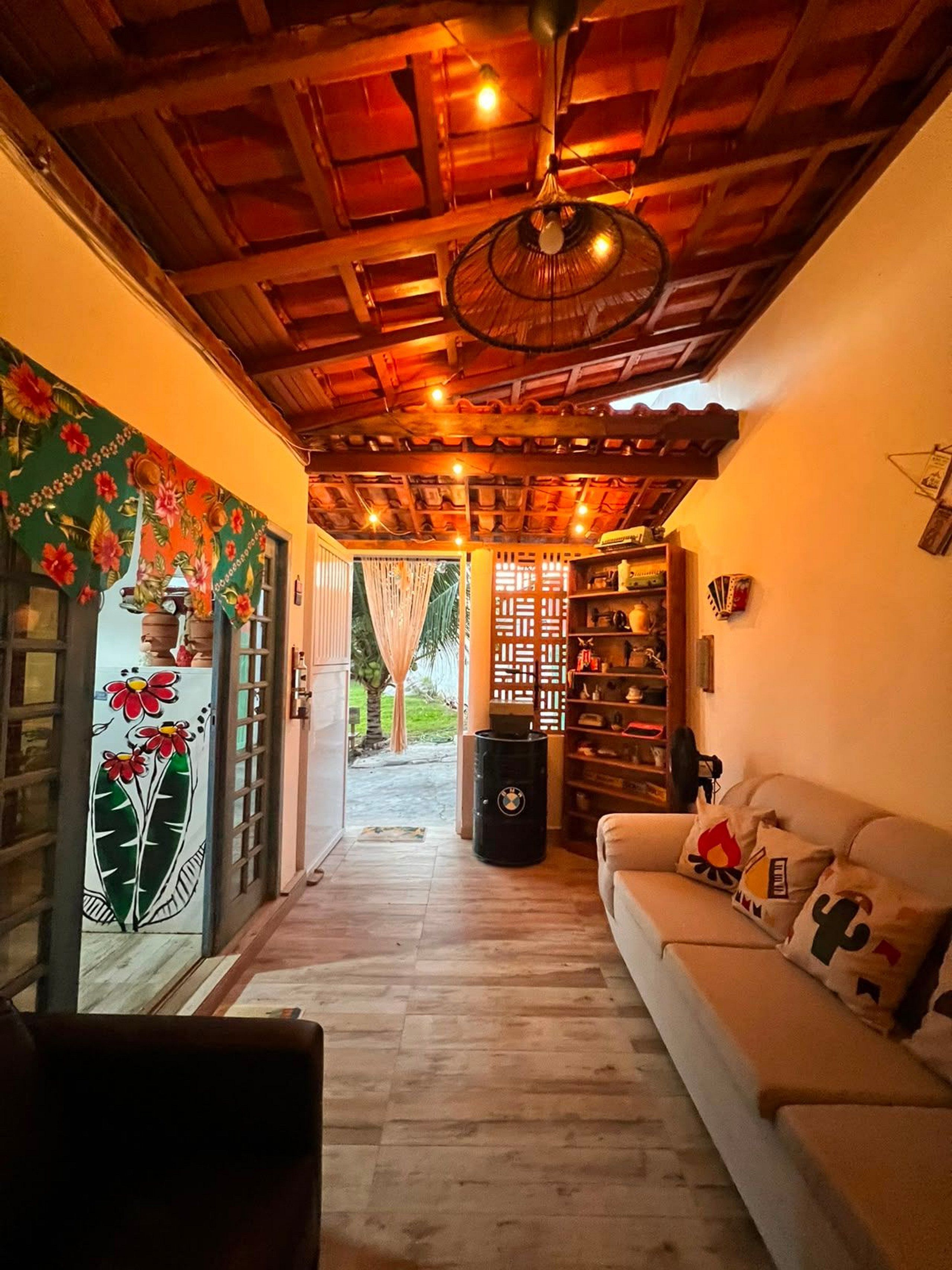 Una sala de estar acogedora con techo de madera, un sofá con almohadones decorativos y una estantería.