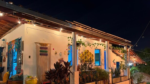 A building with a covered porch, potted plants, and string lights. - Casa Velha Hospedagem Jacuípe (Camaçari)