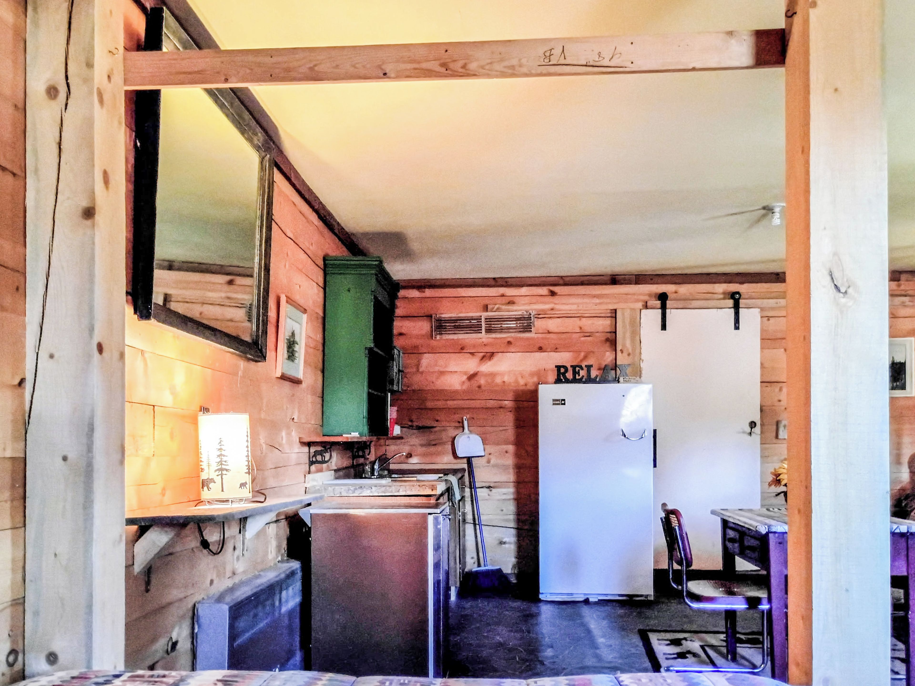 Una cucina compatta con pareti in legno, un frigorifero, un lavello e una zona pranzo con una sedia.