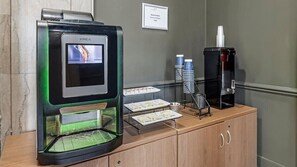 A KREA coffee machine with a digital display, a coffee dispenser, and a menu board on a wooden counter.