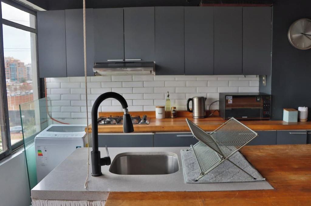 A modern kitchen with a stainless steel sink, a range hood, and a microwave.