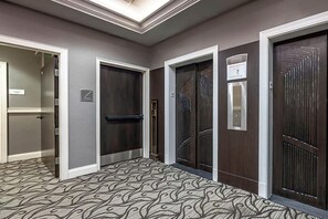 Un couloir avec trois portes, chacune ayant un design différent, qui donnent sur des pièces ou d’autres espaces.