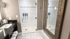 A bathroom with a large mirror, a shower area, and a vanity with a sink and towel rack. - Nashville | Music Lover's City Break | Wi-Fi + Valet (Nashville)