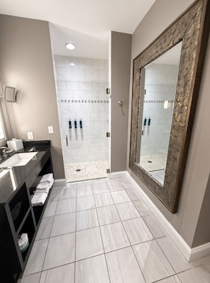 A bathroom with a large mirror, a shower area, and a vanity with a sink and towel rack. - Nashville | Music Lover's City Break | Wi-Fi + Valet (Nashville)