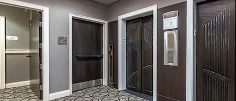 Un couloir avec trois portes, chacune ayant un design différent, qui donnent sur des pièces ou d’autres espaces.