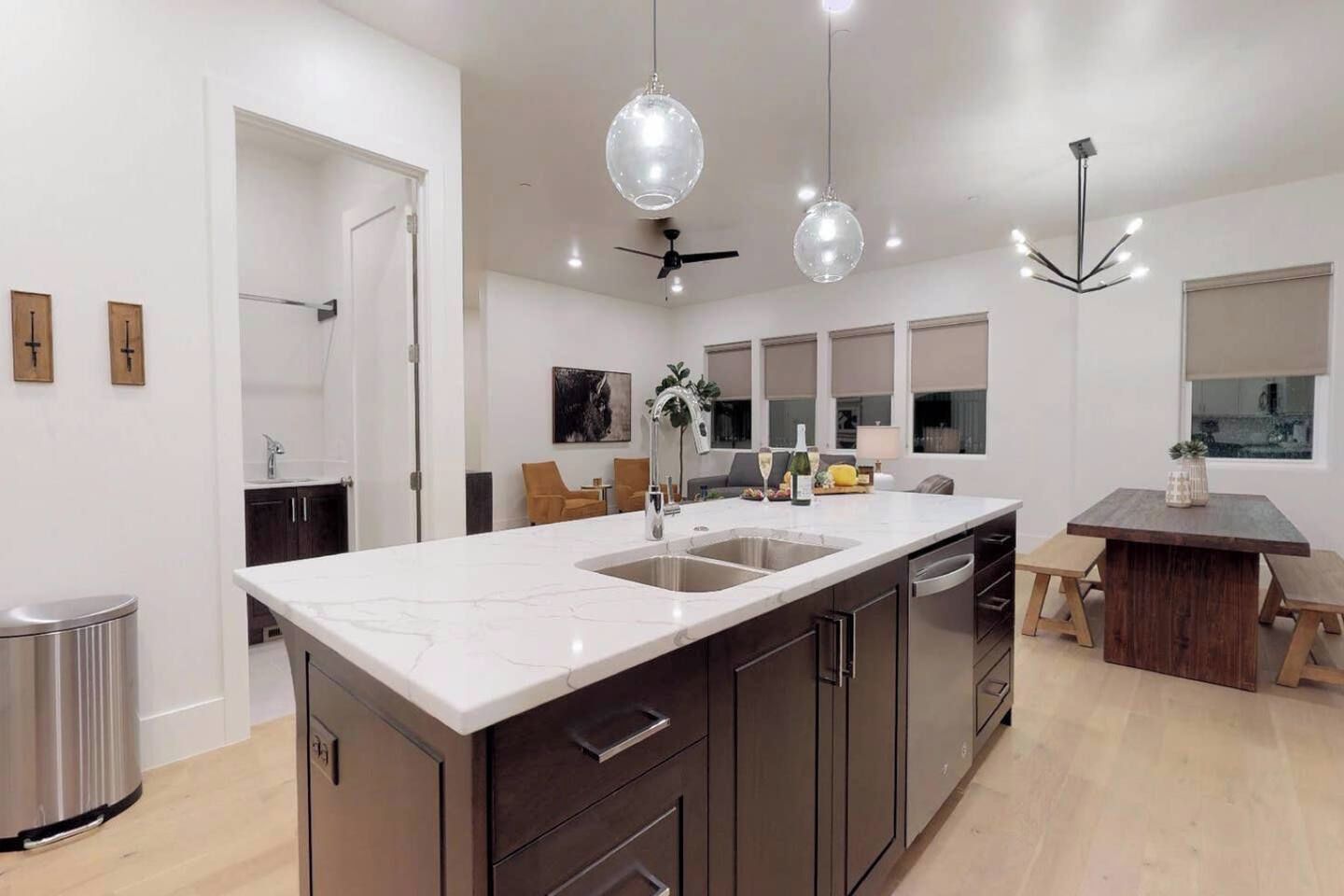 A modern kitchen with a large island, stainless steel appliances, and pendant lighting.