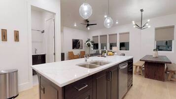 A modern kitchen with a large island, stainless steel appliances, and pendant lighting.
