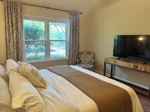 A hotel room with a bed, a television on a wooden stand, and a window with curtains.