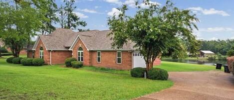 A brick building with a sloped roof, a paved driveway, and a well-maintained lawn.