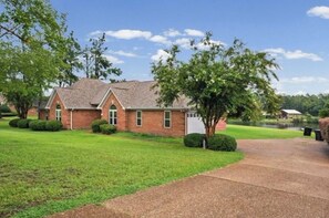 A brick building with a sloped roof, a paved driveway, and a well-maintained lawn.