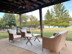 An outdoor patio with wicker furniture, a table, and a view of a lake.