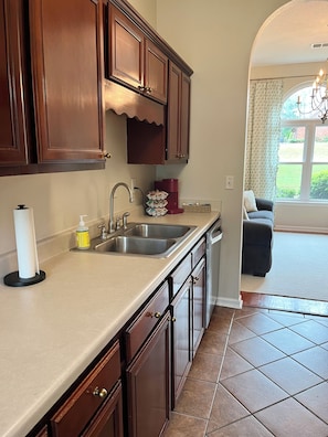 A kitchen with dark wooden cabinets, a double sink, and a coffee maker. - Cedar Lake Cottage • Pool & Lake view! (Oxford)