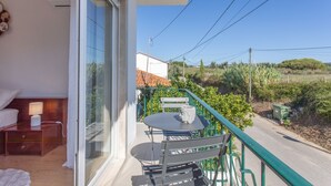 Un balcon avec une table et une chaise, un lit avec une lampe et une vue sur la campagne.