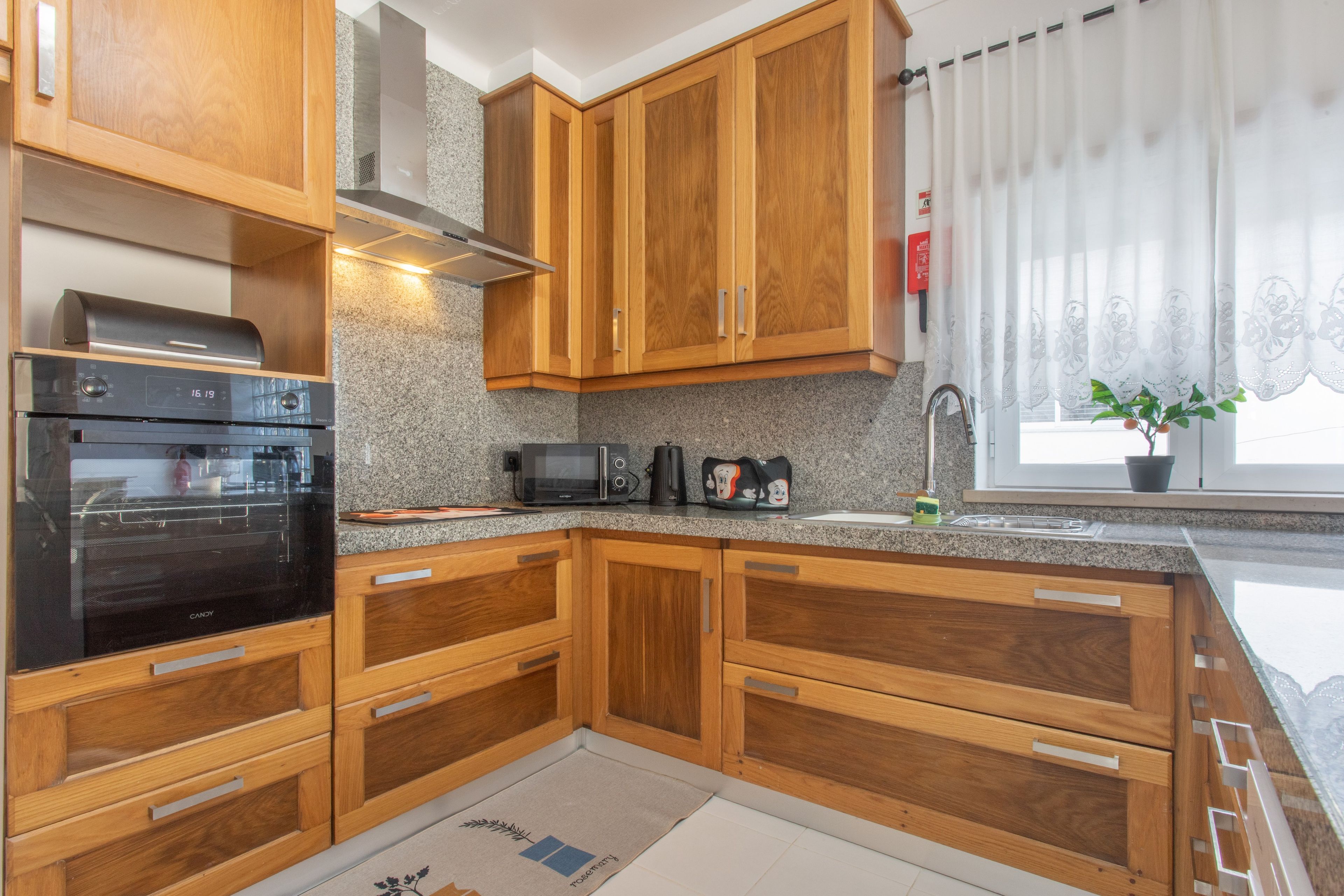 Una cocina con armarios de madera, un microondas, un tostador y un lavamanos.