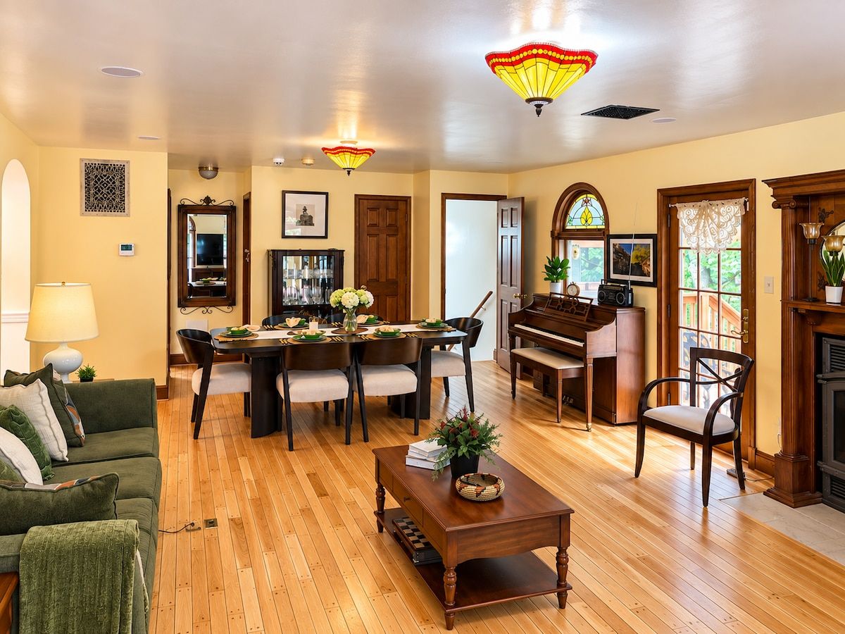 A spacious living room with a dining area, a piano, and a fireplace.