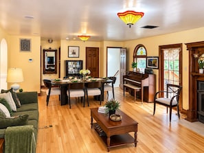 Una sala de estar amplia con comedor, un piano y una chimenea.