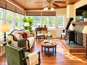 A cozy living room with a fireplace, comfortable seating, and large windows.