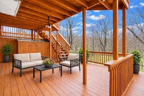 A wooden deck with a sofa, chairs, and a table with a flower arrangement.