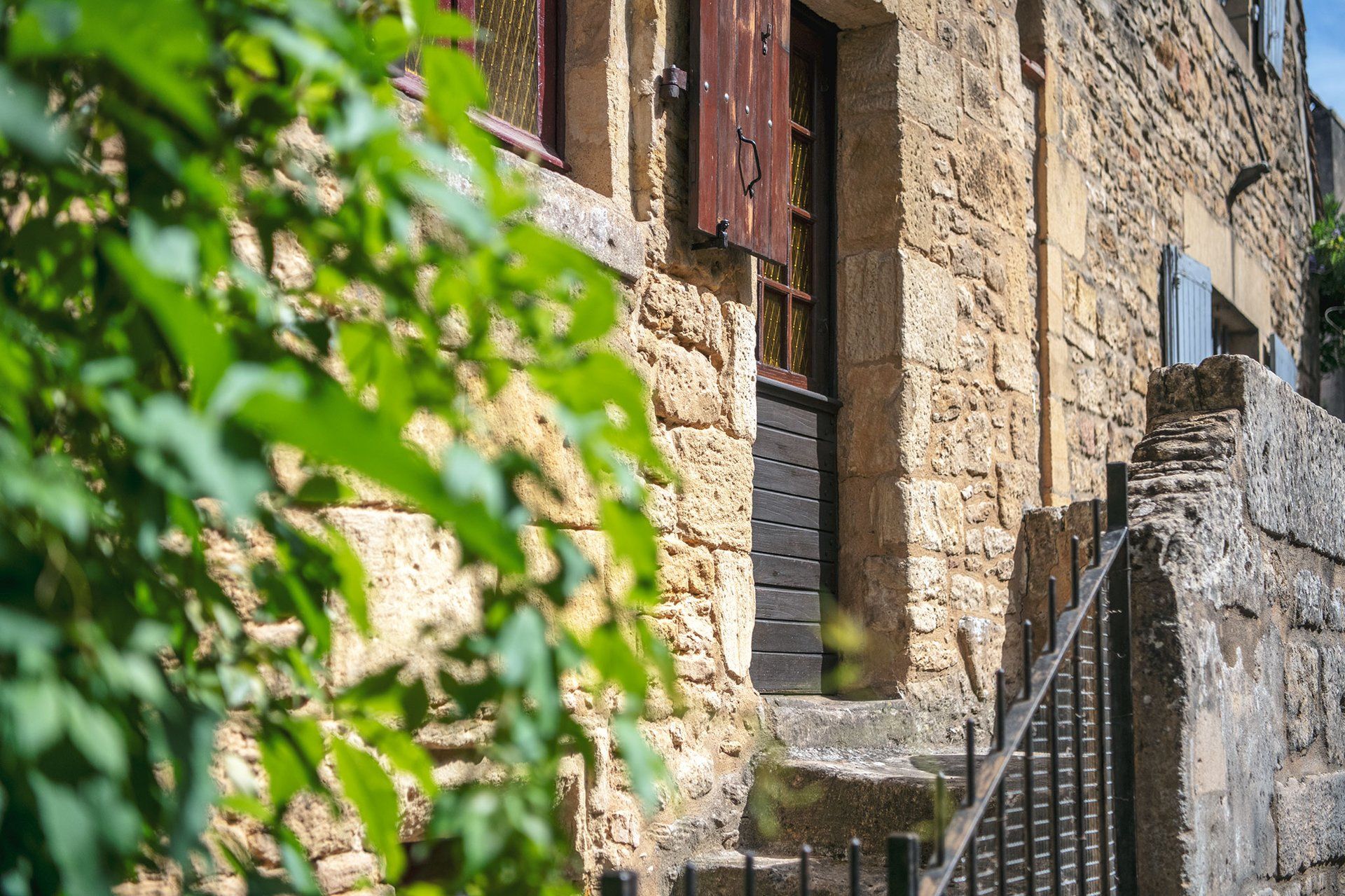 A stone building with a wooden staircase leading to a door with a metal handle.