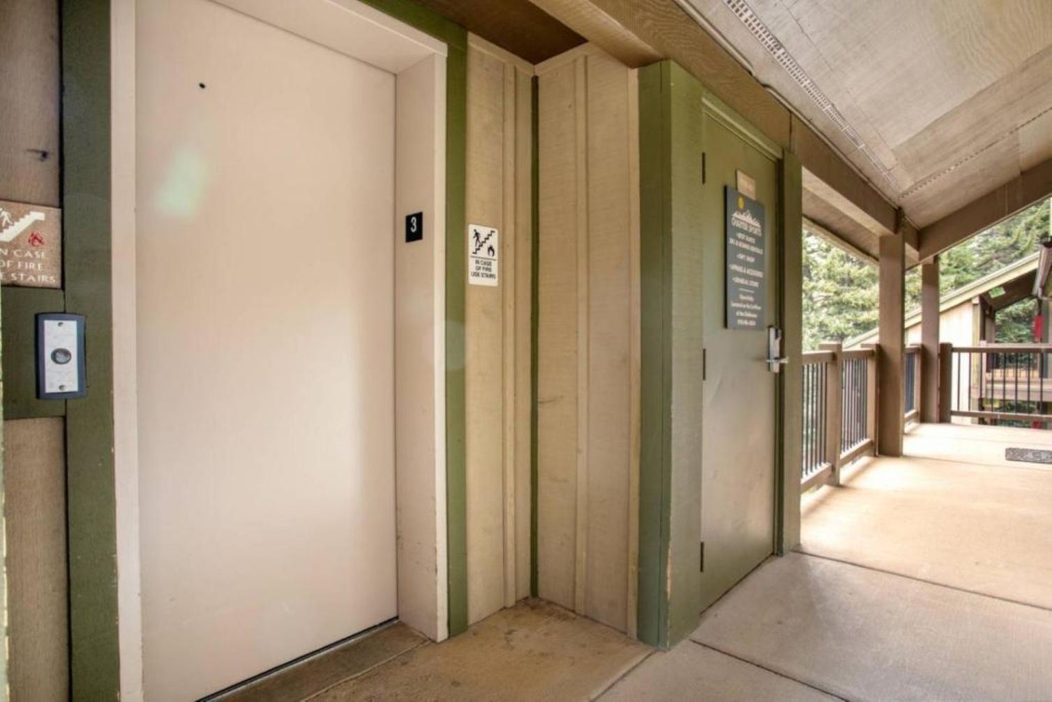 A hotel entrance with a closed door, a fire safety sign, and a wheelchair-accessible ramp.