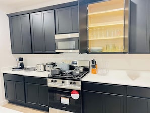 A modern kitchen with black cabinets, stainless steel appliances, and a built-in microwave. - 5BR Single-Story | Pet Friendly | Fenced Yard (Rosenberg)