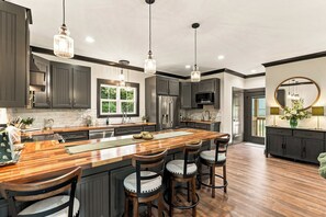 A spacious kitchen with a central island, bar stools, and pendant lighting. - Honey's Hideaway I An Exclusive TN River Retreat! (Birchwood)