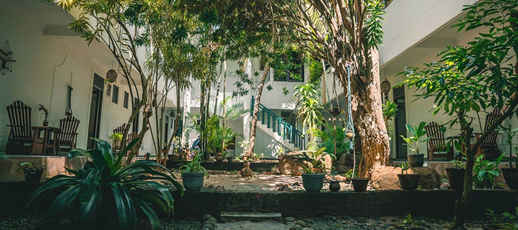 A courtyard with potted plants, a staircase, and outdoor furniture.