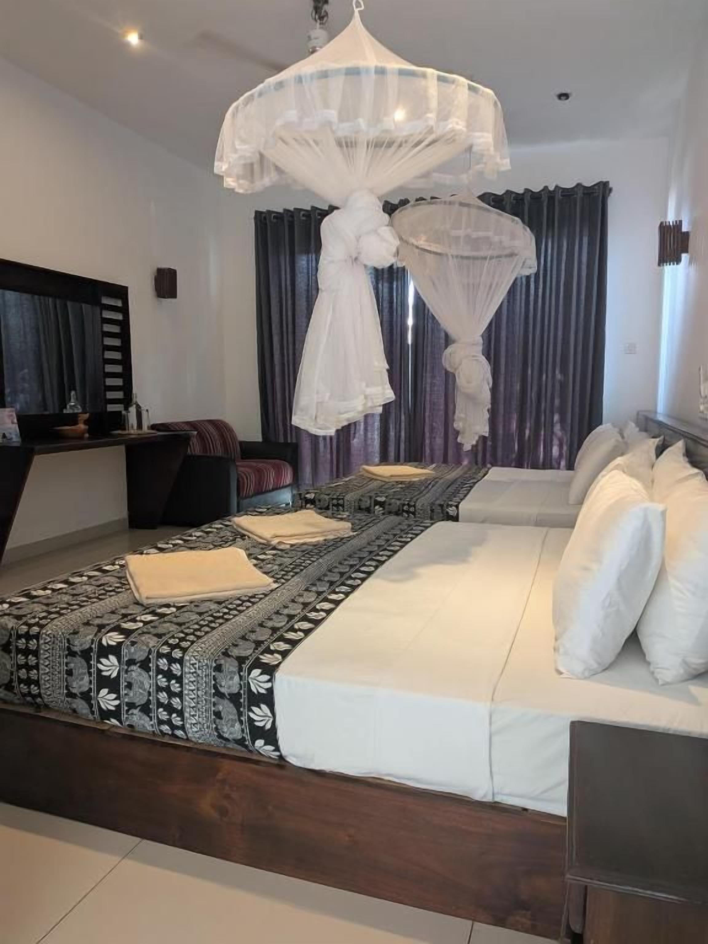 A bedroom with a bed, bedside tables, a canopy bed, and a large window with curtains.
