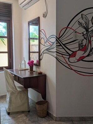 Una habitación con escritorio, silla y una pared con un mural decorativo.