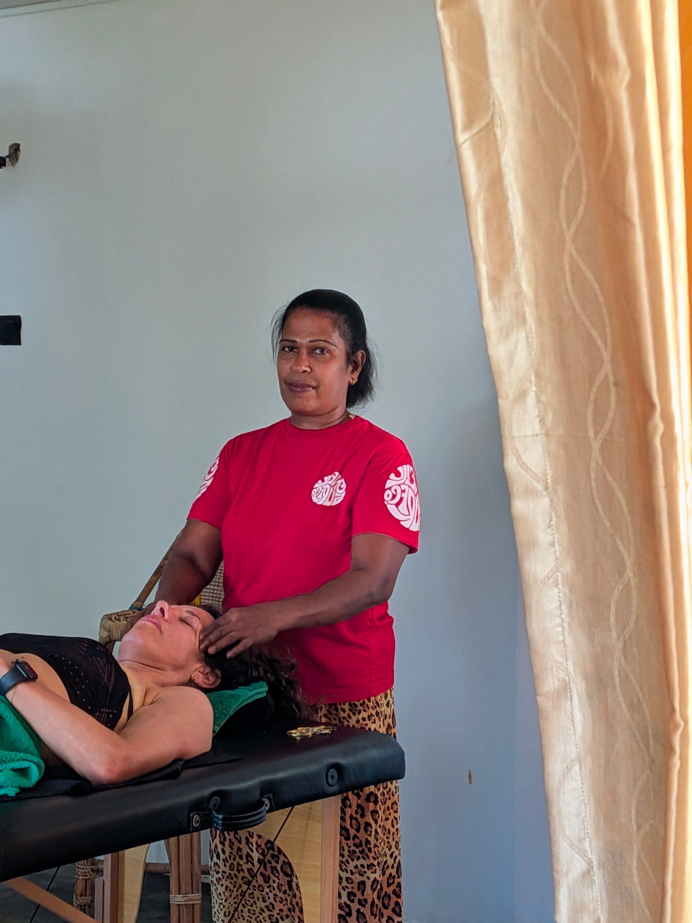 A person lying on a massage table receiving a back massage from another individual.