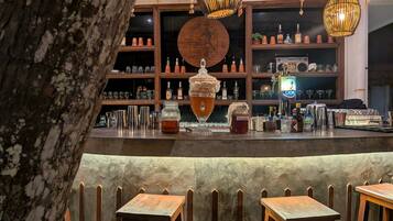 Una zona de bar con estantes de madera, mostrador y luces colgantes.