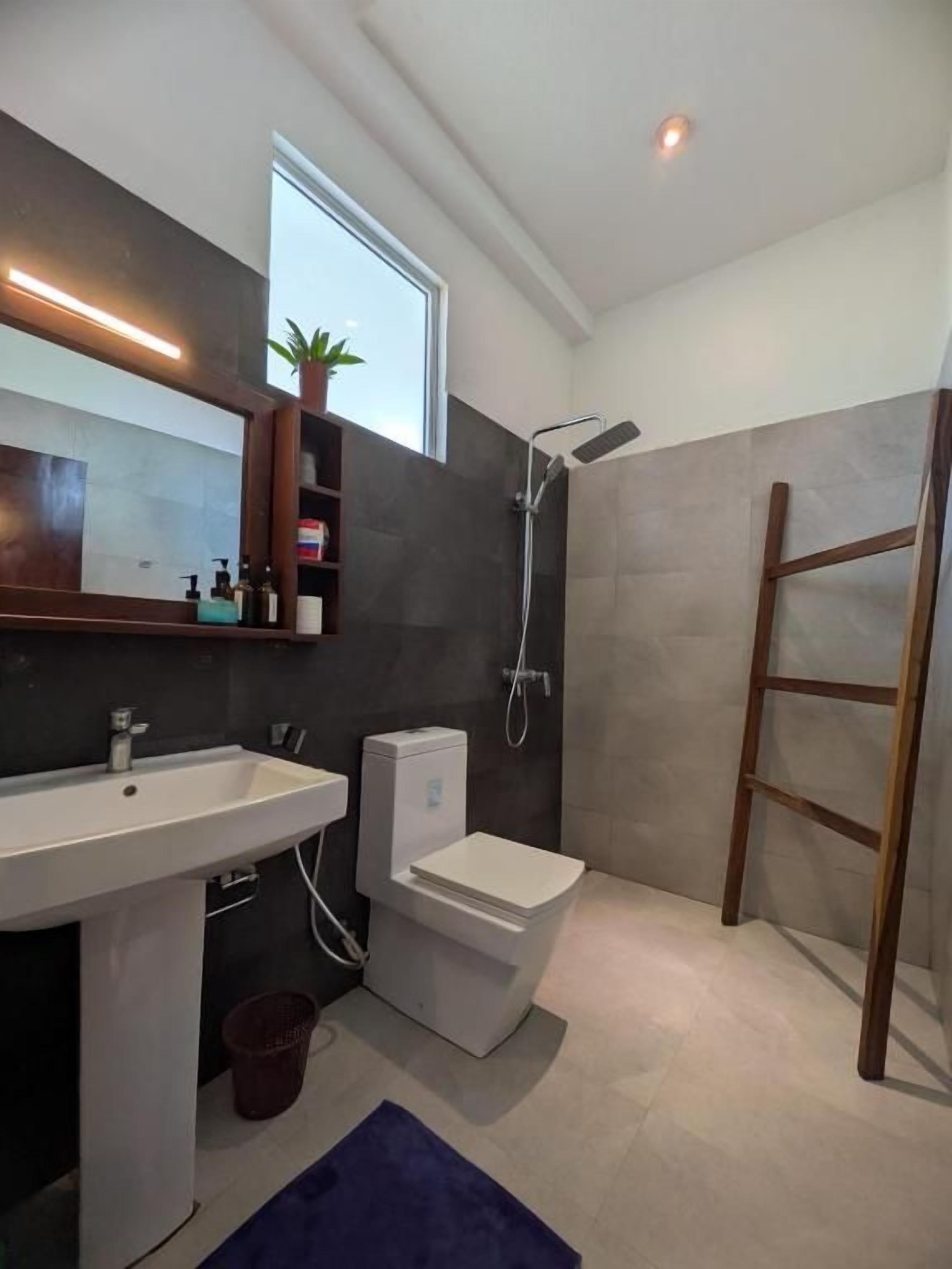 Un baño moderno con lavamanos, inodoro y ducha.