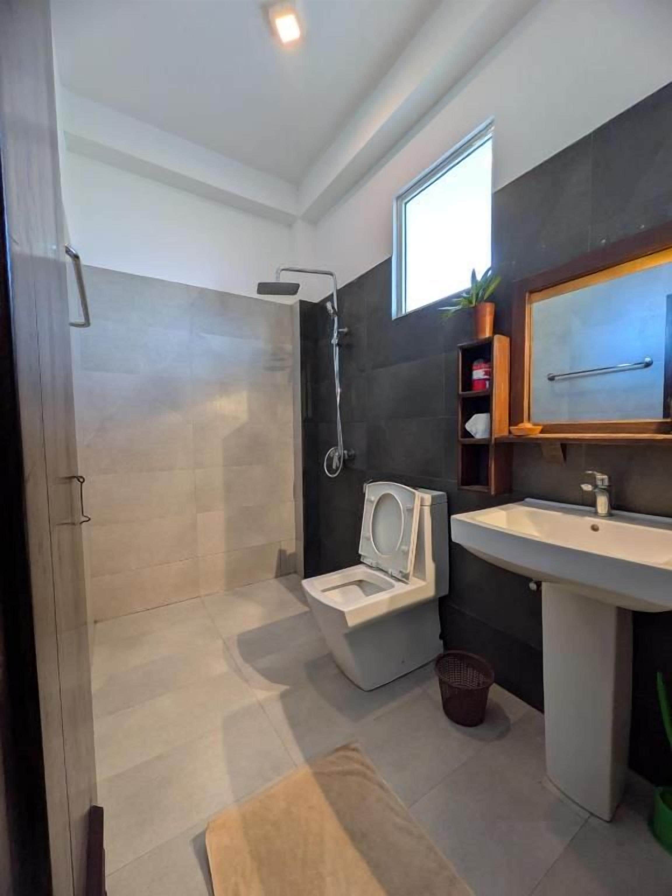 A modern bathroom with a shower, toilet, and sink.