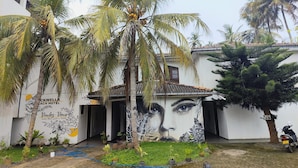 A building with a mural of a face, palm trees, and a sign for 'CKWELLA BEACH HOTEL'. - Dickwella Beach Hotel (Dikwella)