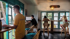 A room with a computer, a person working at a desk, and another person seated at a table. - Dickwella Beach Hotel (Dikwella)