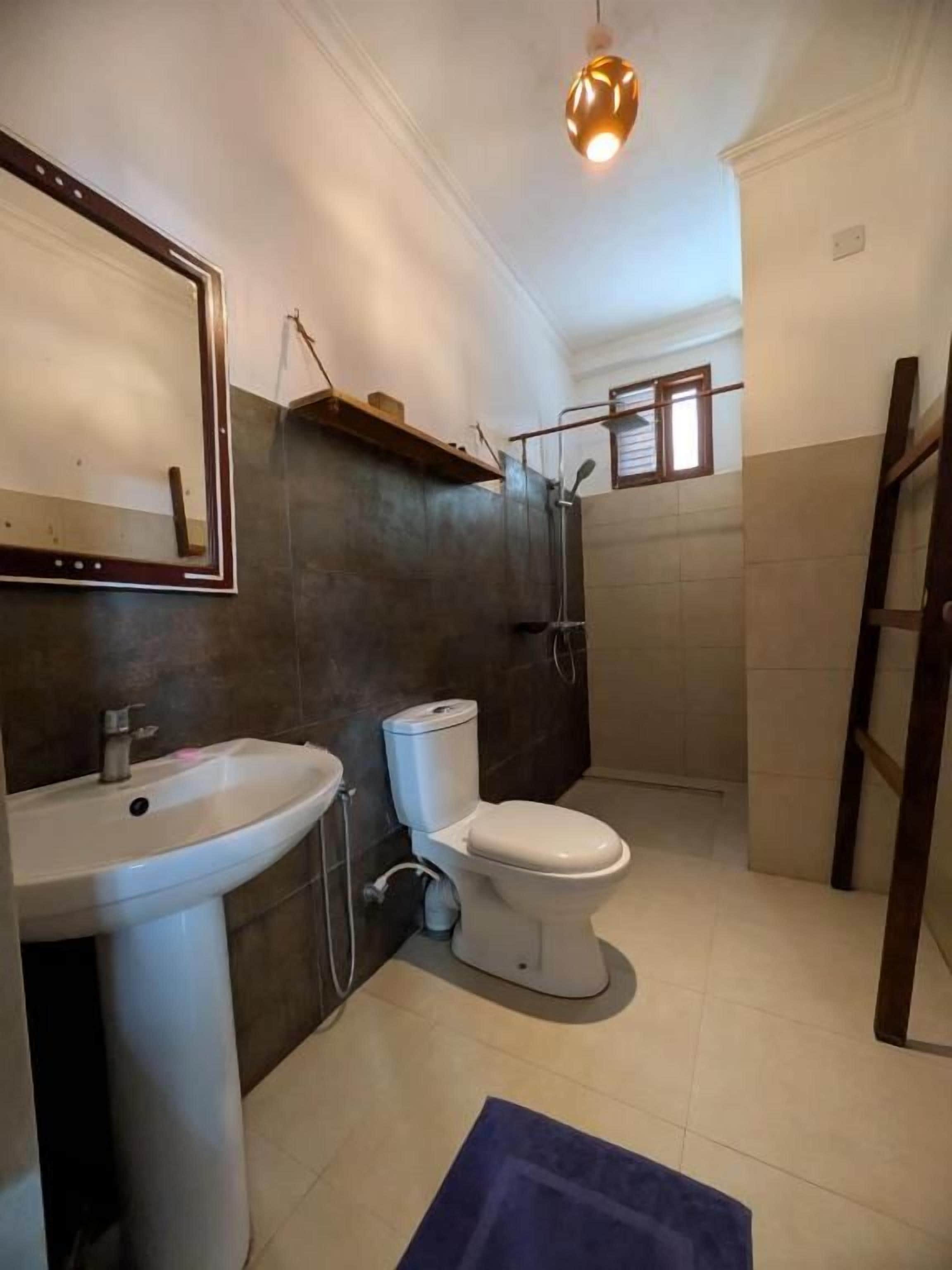 Et badeværelse med vask, toilet og bruseområde.