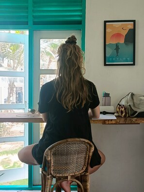 Eine Person sitzt an einem Schreibtisch mit Blick ins Freie durch ein Fenster.