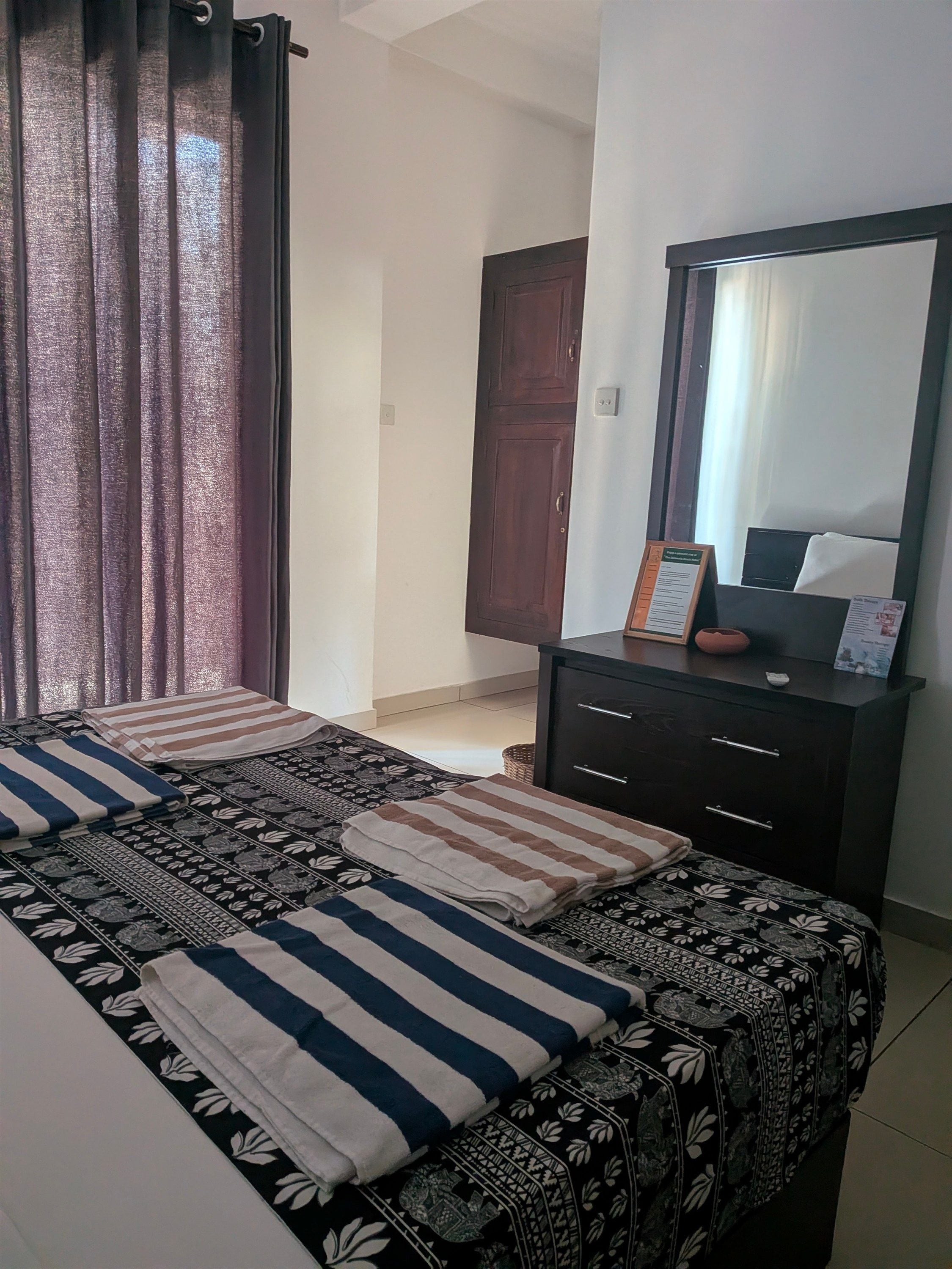 Une chambre d’hôtel avec un lit, une commode, un miroir et une porte.