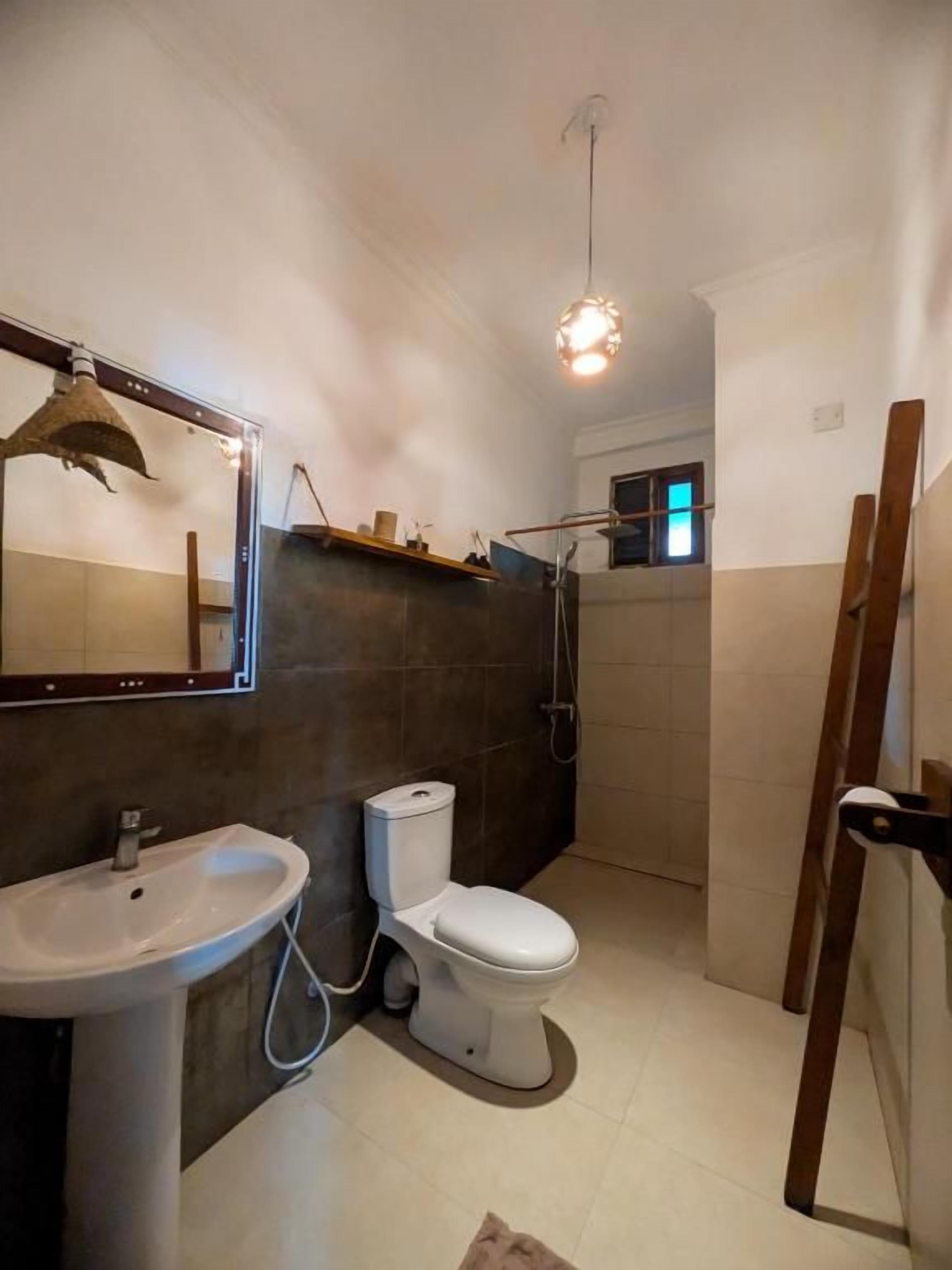 Et badeværelse med håndvask, toilet og bruser.