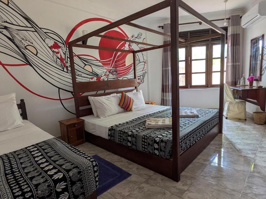 Een kamer met een hemelbed, een groot abstract wandtapijt, een raam met gordijnen en een klein nachtkastje.