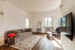 A modern living room with a sofa, a coffee table, a TV, and a window. - Como In The Sky - 150 steps, by MyHomeInComo (Como)
