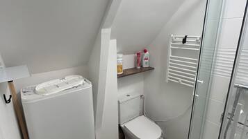 Ein kleines, modernes Badezimmer mit Toilette, Bidet und einer Duschkabine aus Glas.