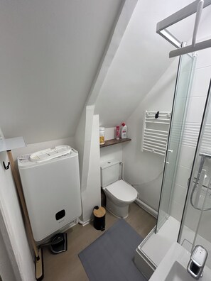 Et stilfuldt, moderne badeværelse med toilet, bidet og en glasvæg omkring brusebadet.