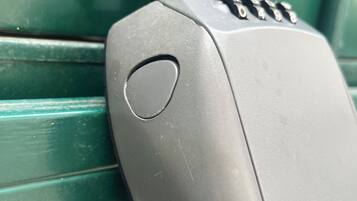 En metalkasse med et tastatur, muligvis en sikkerhedsanordning, fastgjort til en grøn metaloverflade.