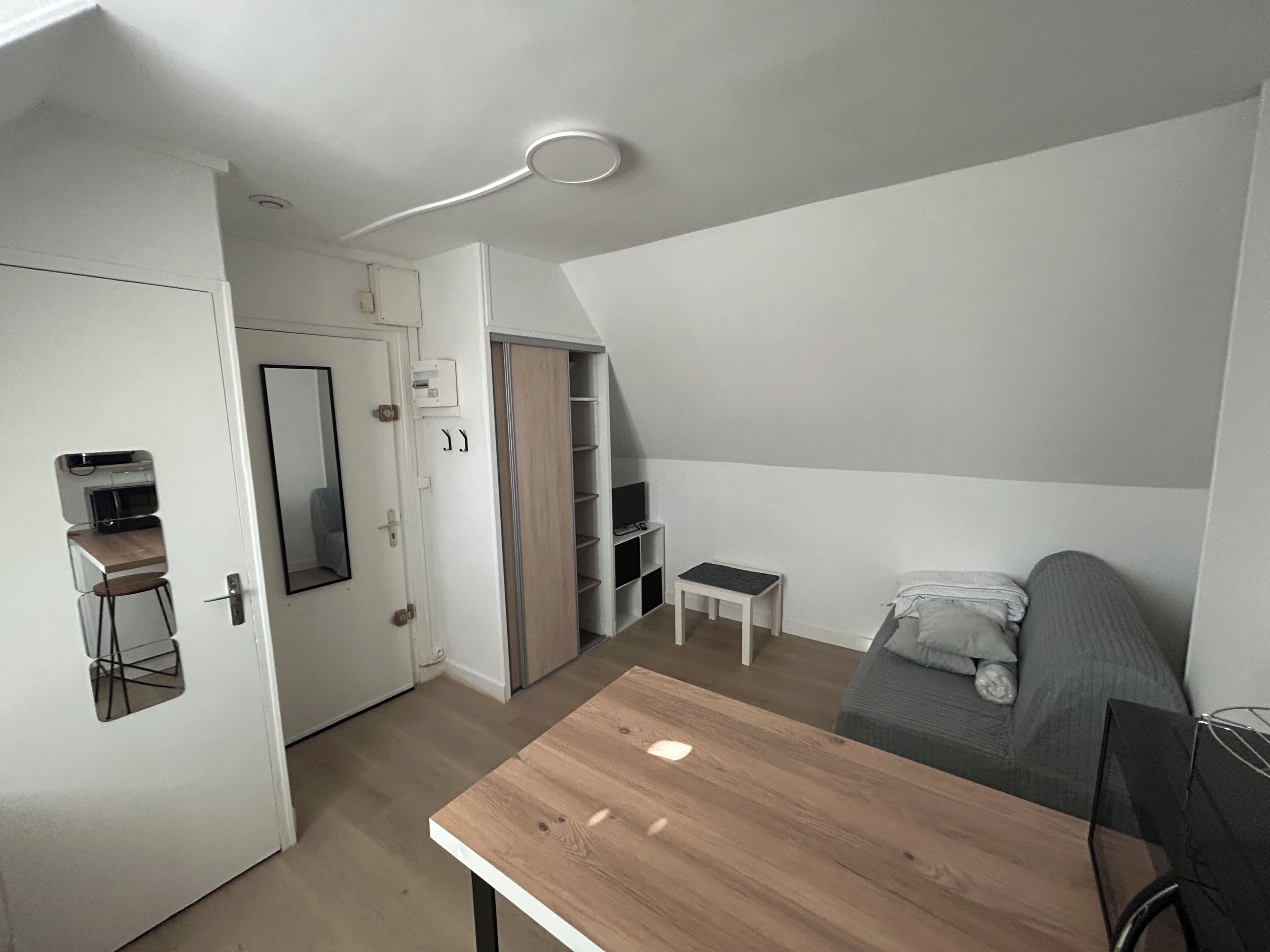 En kompakt opholdsstue med et tekøkken, et spisebord og en sofa.