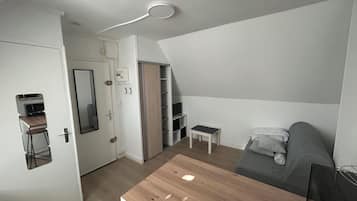 En kompakt opholdsstue med et tekøkken, et spisebord og en sofa.