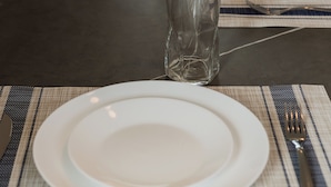 A table set with a plate, a glass, and a napkin on a placemat. - Brisa  (Cancún)
