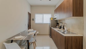 A modern kitchen with a dining area, wooden cabinets, a stainless steel sink, and a ceiling fan. - Brisa  (Cancún)